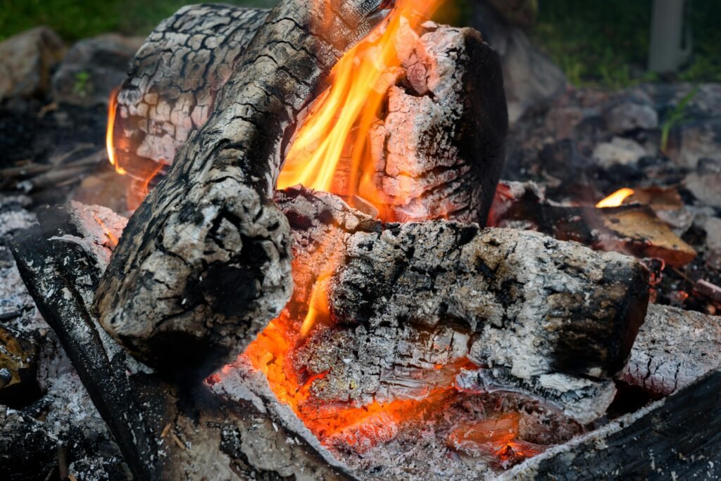A detailed view of a campfire with burning logs and vibrant flames, ideal for outdoor and camping themes.