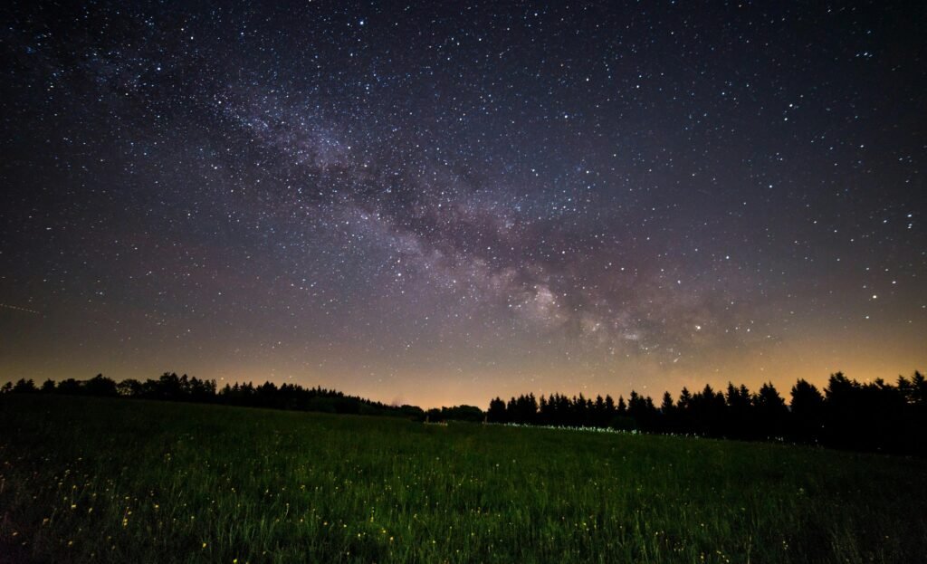 A breathtaking view of a starry night sky over a quiet field, showcasing the Milky Way.